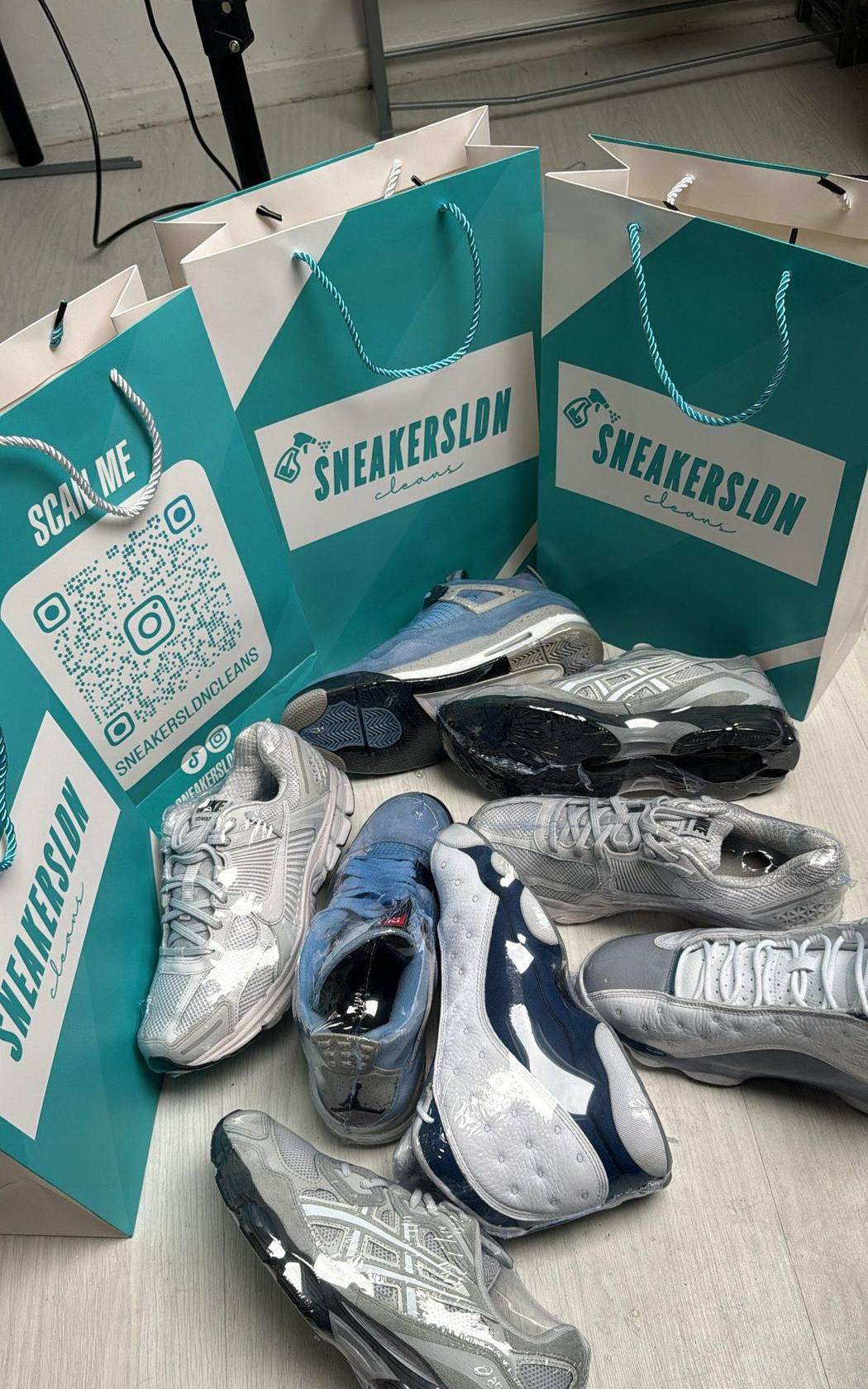 Freshly cleaned pairs sleek-wrapped beside Sneakersldncleans' branded teal bags